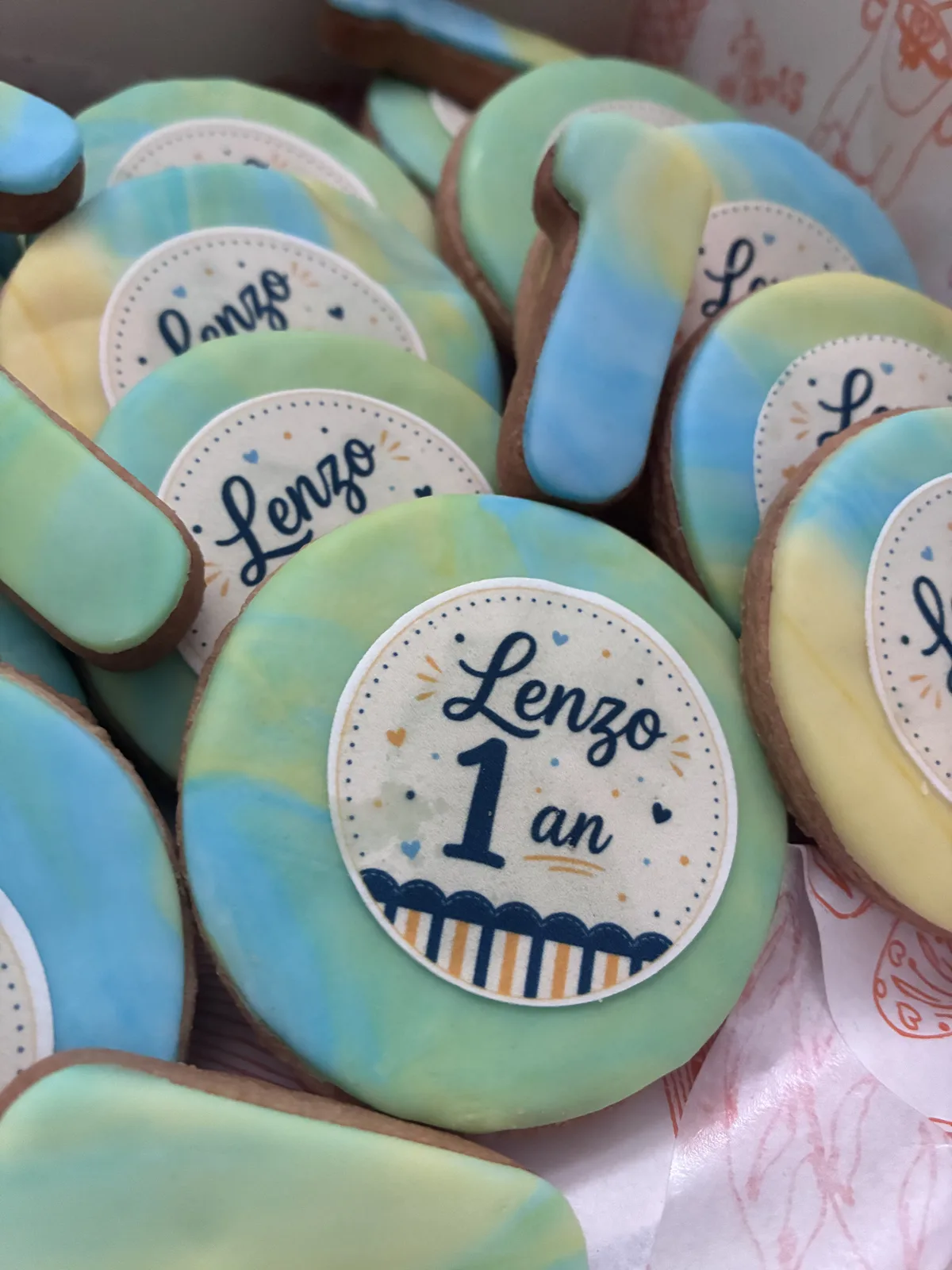 Biscuits sablés ronds au glaçage marbré bleu, vert et jaune, médaillon comestible « Lenzo 1 an »