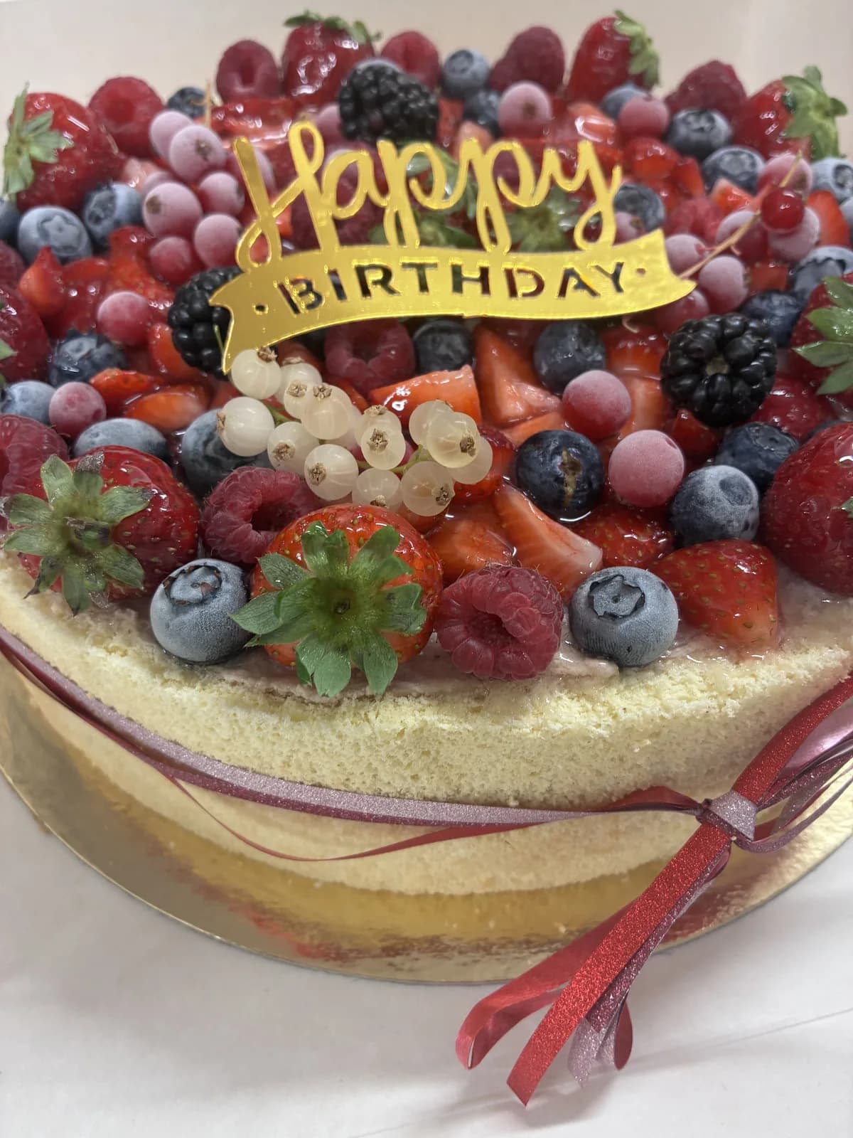 Gâteau façon naked cake recouvert de fraises, framboises, myrtilles et mûres fraîches, topper doré Happy Birthday